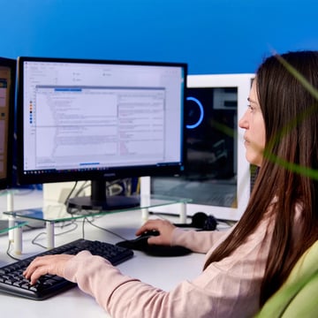 Full stack developer al lavoro in ufficio davanti al computer mentre inserisce righe di codice.