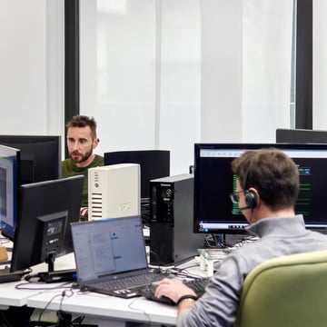 Full stack developers al lavoro in ufficio davanti a molteplici monitor.